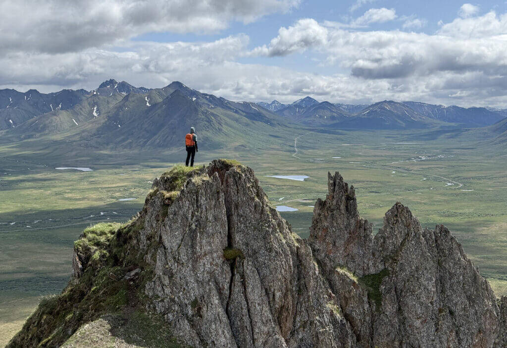 Ein Mann auf einem Felsen, im Hintergrund Berge